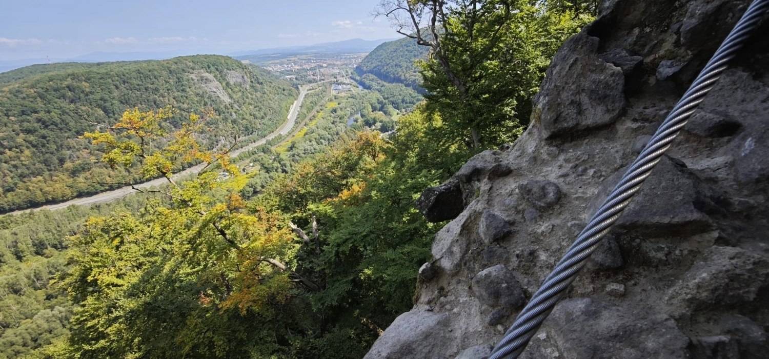 Oceľové istiace lano ferraty vedené po skale nad dolinou